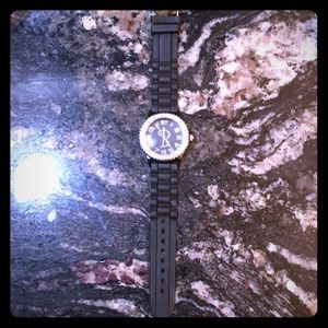 Black watch with an B on the face of the watch